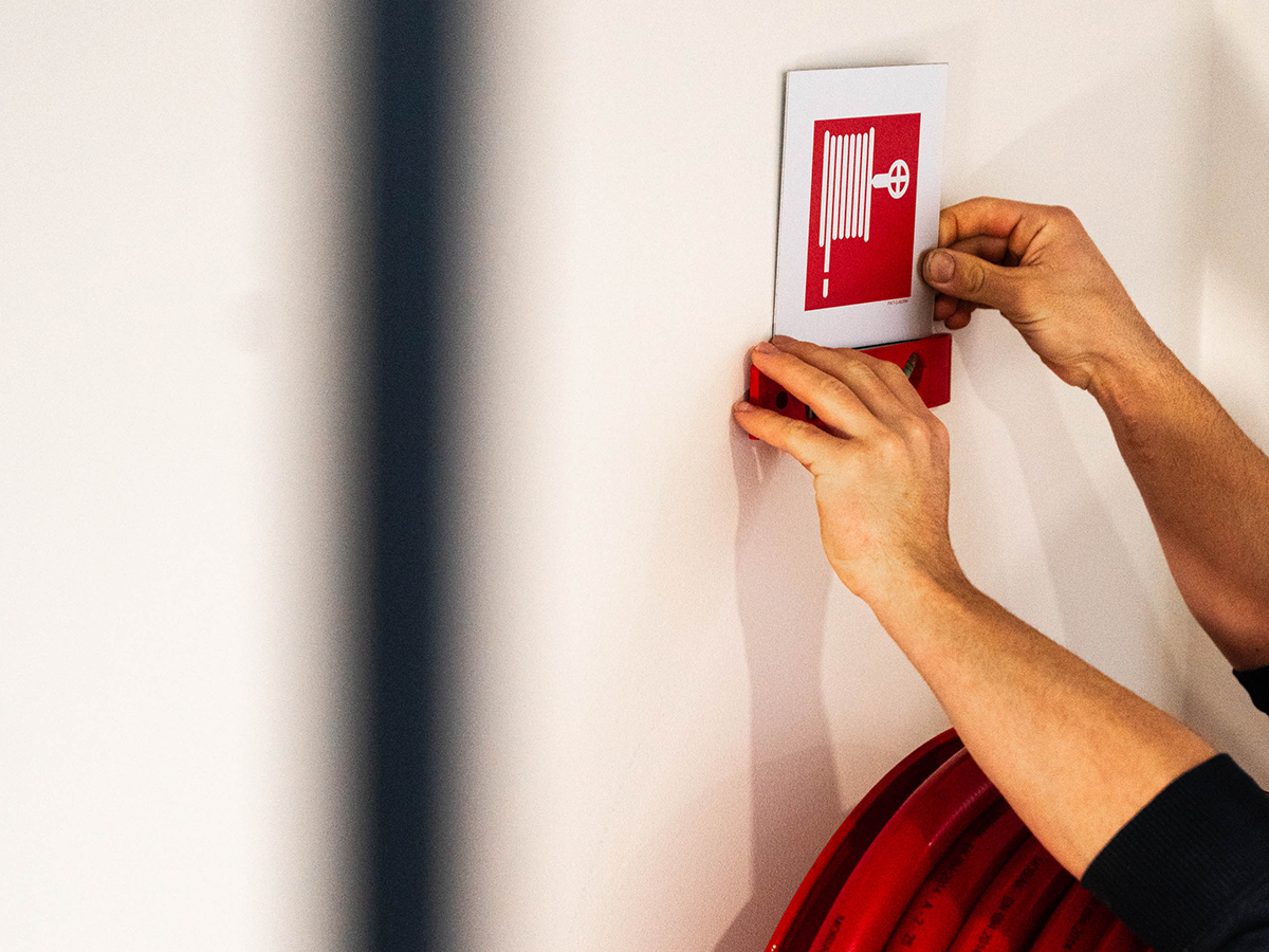 FYRCO-technieker plaatst een pictogram voor een brandhaspel op de muur.